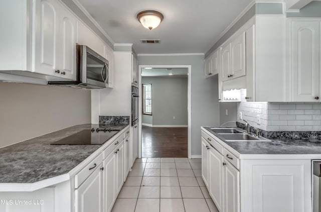 kitchen with appliances with stainless steel finishes, sink, white cabinets, ornamental molding, and light tile patterned floors