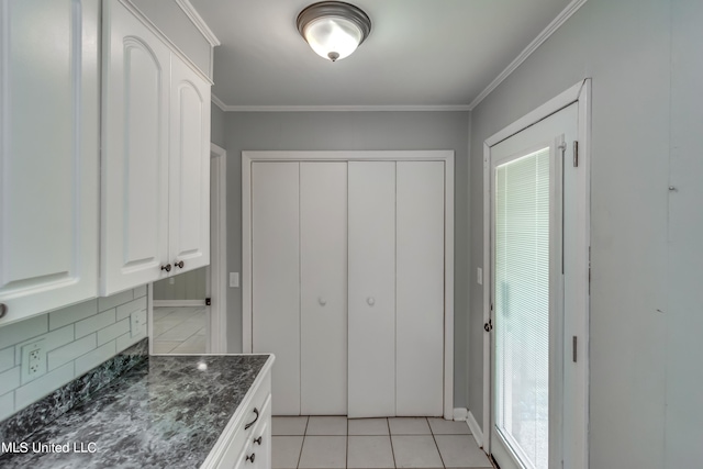 kitchen with tasteful backsplash, ornamental molding, light tile patterned floors, and white cabinets
