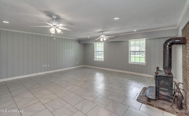 living room featuring ornamental molding, a wood stove, wood walls, and ceiling fan