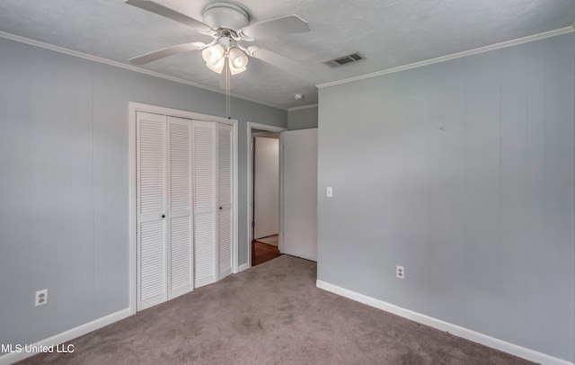 unfurnished bedroom featuring carpet, crown molding, a closet, and ceiling fan