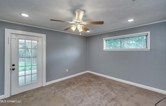 empty room with crown molding, ceiling fan, carpet flooring, and plenty of natural light