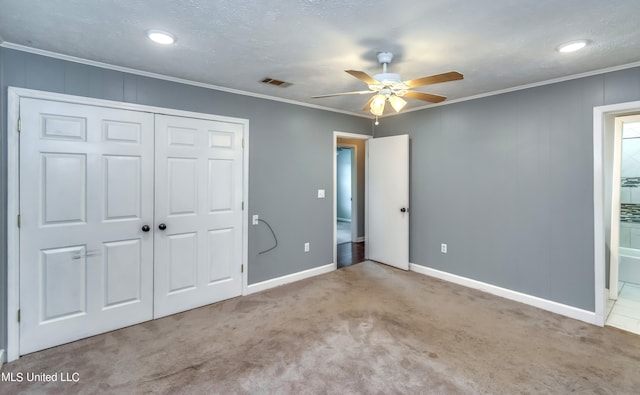 unfurnished bedroom featuring light carpet, ceiling fan, a textured ceiling, ornamental molding, and a closet