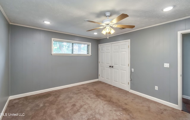unfurnished bedroom featuring a closet, carpet floors, crown molding, and ceiling fan