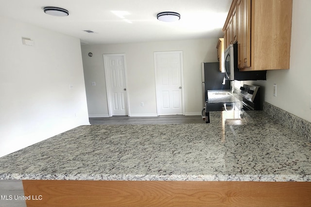 2708 Canty St, Pascagoula, MS 39567 - kitchen with electric stove, brown cabinetry, wood finished floors, light stone countertops, and stainless steel microwave