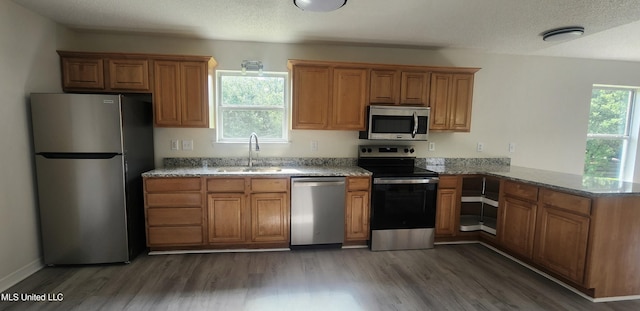 2708 Canty St, Pascagoula, MS 39567 - kitchen featuring appliances with stainless steel finishes, brown cabinets, dark wood-style flooring, stone countertops, and a peninsula