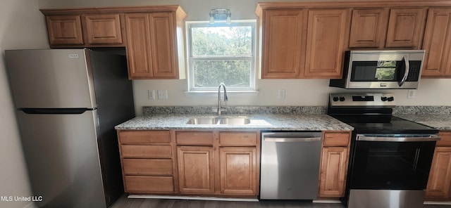 2708 Canty St, Pascagoula, MS 39567 - kitchen with appliances with stainless steel finishes, light stone counters, brown cabinetry, and wood finished floors