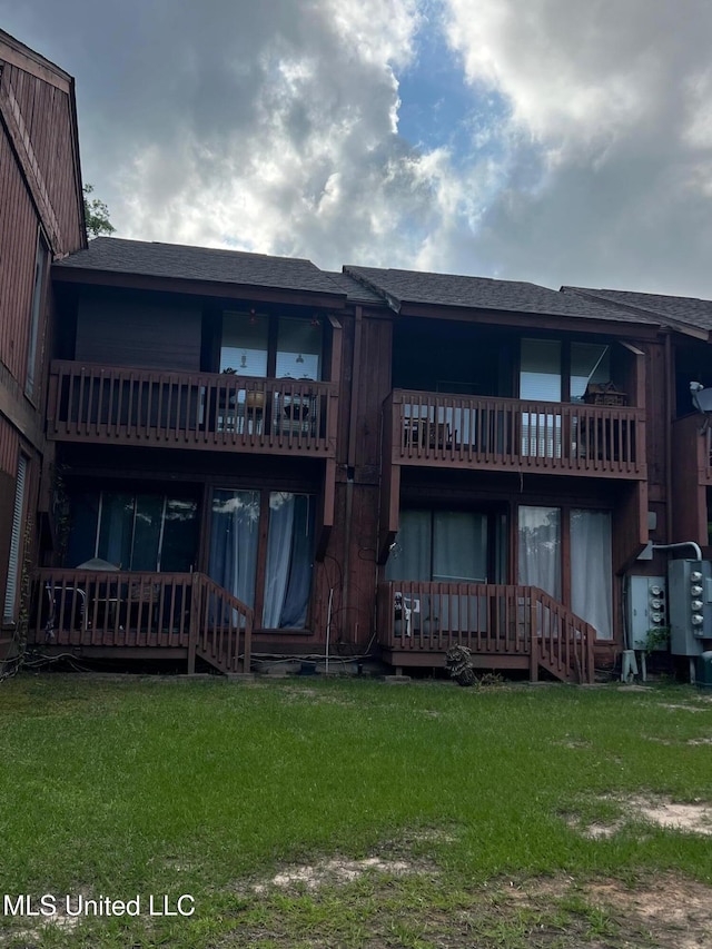 206 Lakeside Villa Unit A, Diamondhead, MS 39525 - back of house featuring a lawn, a shingled roof, and a balcony