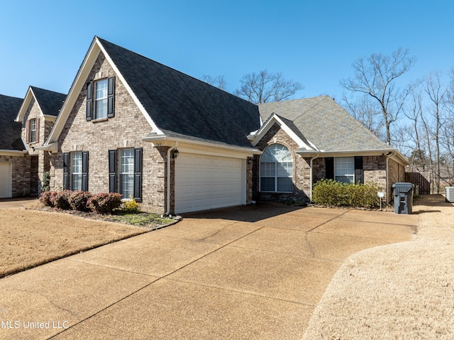 view of front of house with concrete driveway, brick siding, an attached garage, and roof with shingles