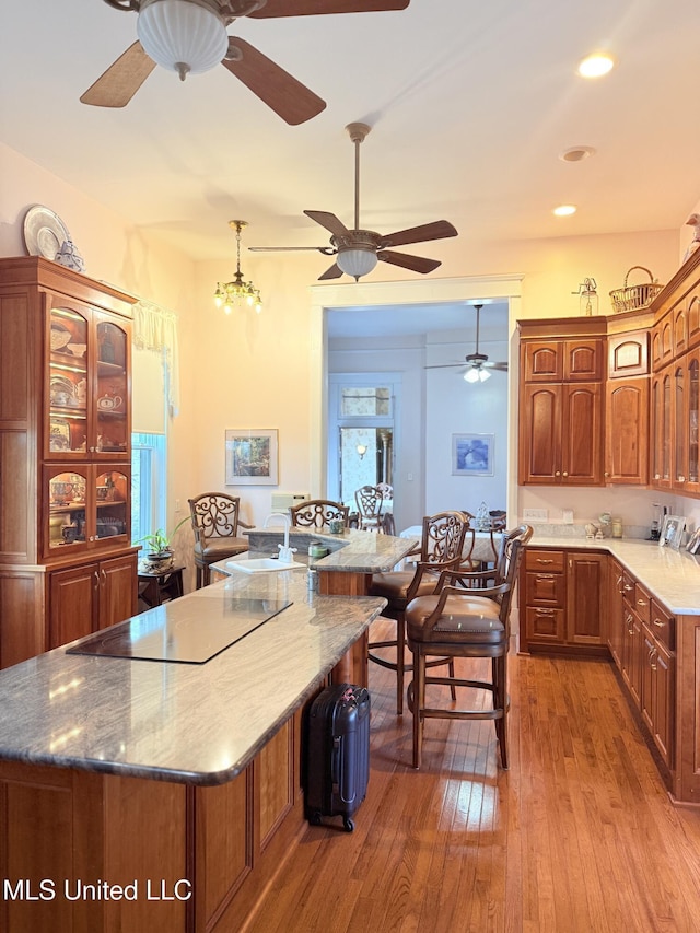 5 Spruce St, Oakland, MS 38948 - kitchen featuring a center island, glass insert cabinets, hardwood / wood-style flooring, brown cabinetry, and black electric cooktop