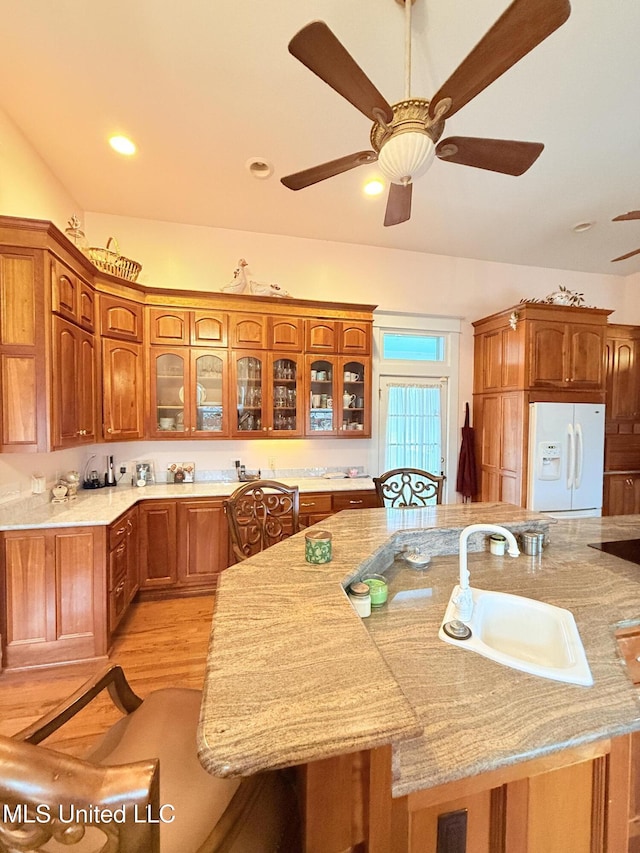 5 Spruce St, Oakland, MS 38948 - kitchen with glass insert cabinets, light wood-type flooring, brown cabinets, white refrigerator with ice dispenser, and a sink