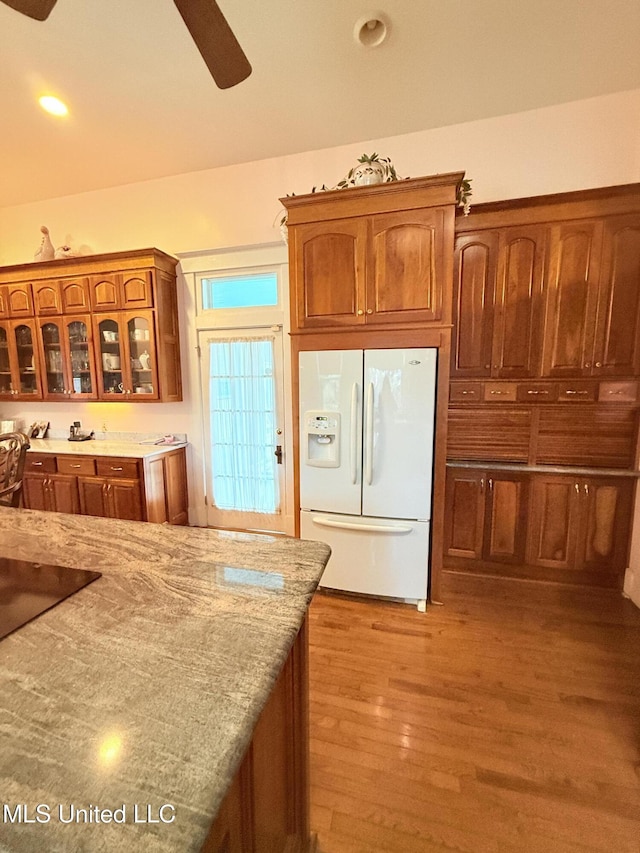 5 Spruce St, Oakland, MS 38948 - kitchen with light stone counters, brown cabinetry, light wood finished floors, white refrigerator with ice dispenser, and glass insert cabinets