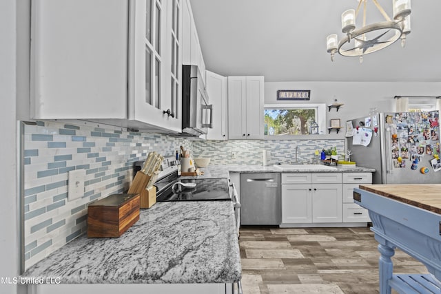 kitchen with white cabinetry, light hardwood / wood-style floors, stainless steel appliances, and hanging light fixtures