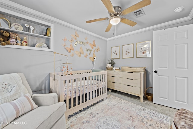 carpeted bedroom featuring ceiling fan, crown molding, and a crib