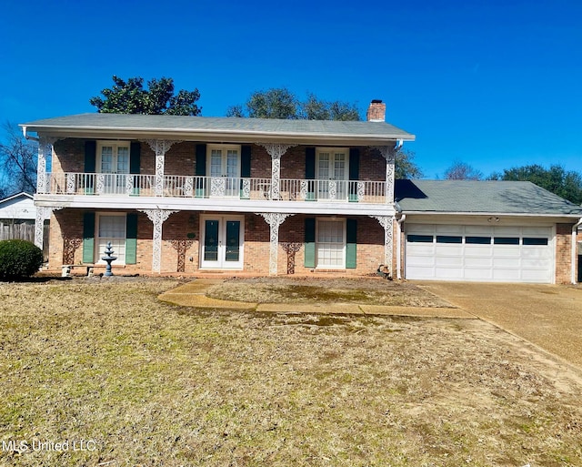 view of front of home with driveway, french doors, a front lawn, and brick siding