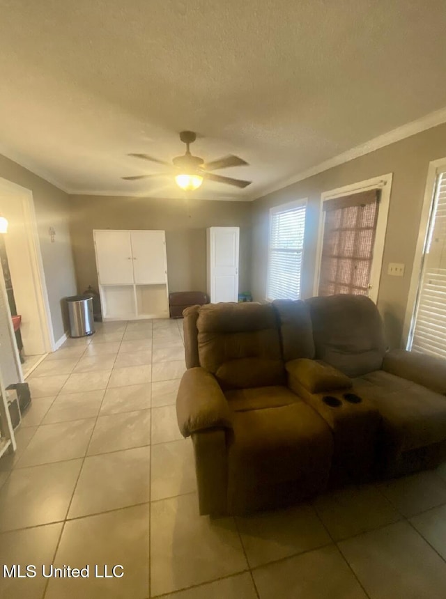 living room featuring ceiling fan, ornamental molding, a textured ceiling, and light tile patterned flooring