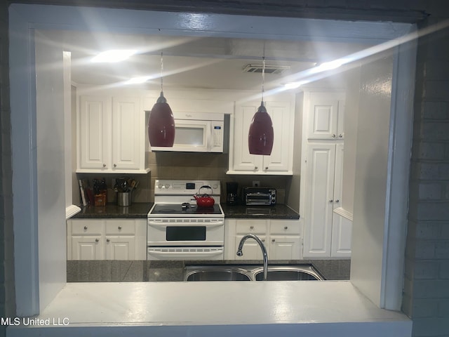 kitchen featuring white appliances, a sink, visible vents, white cabinets, and dark countertops