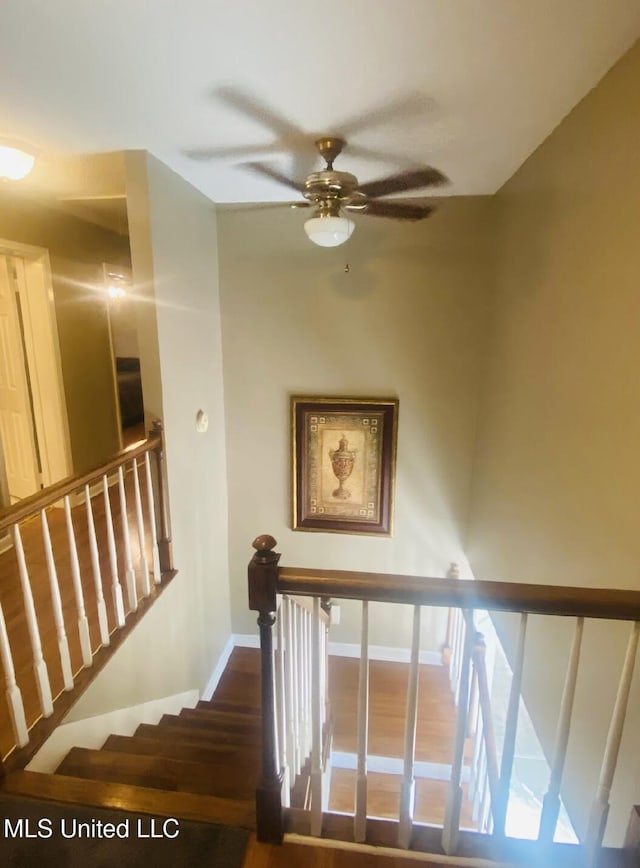 stairs with ceiling fan and baseboards