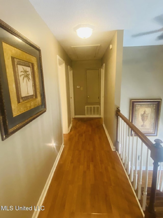 hallway featuring visible vents, attic access, an upstairs landing, wood finished floors, and baseboards