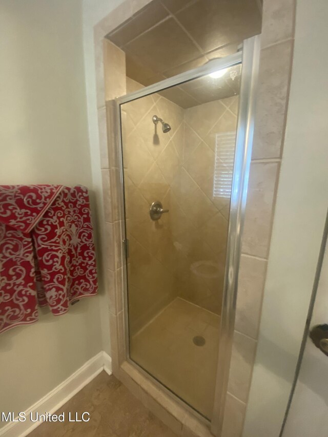 bathroom featuring a stall shower, tile patterned flooring, and baseboards