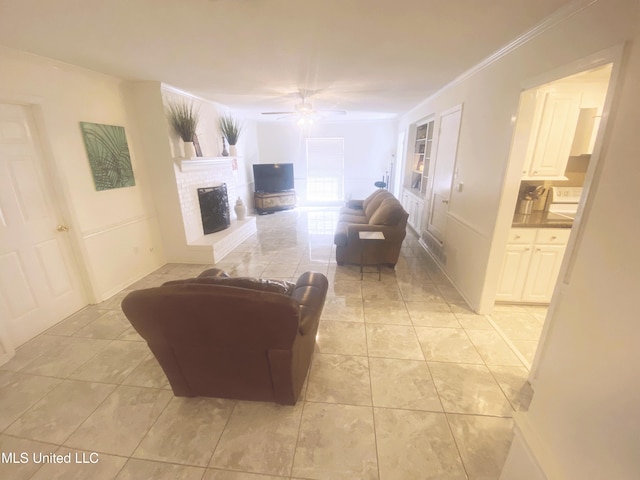 living room featuring a ceiling fan, ornamental molding, a brick fireplace, built in shelves, and light tile patterned flooring