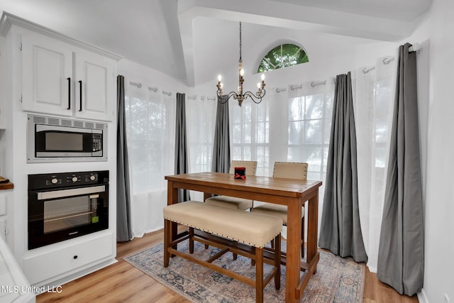 dining room with light hardwood / wood-style flooring, a chandelier, and vaulted ceiling