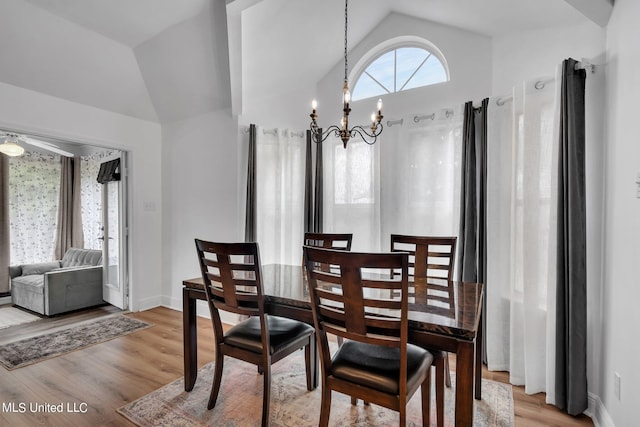 dining area featuring a notable chandelier, light wood-type flooring, and vaulted ceiling