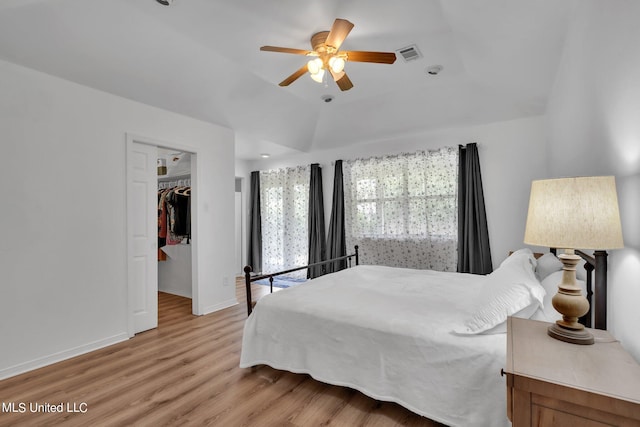 bedroom with a walk in closet, a closet, ceiling fan, lofted ceiling, and light hardwood / wood-style flooring