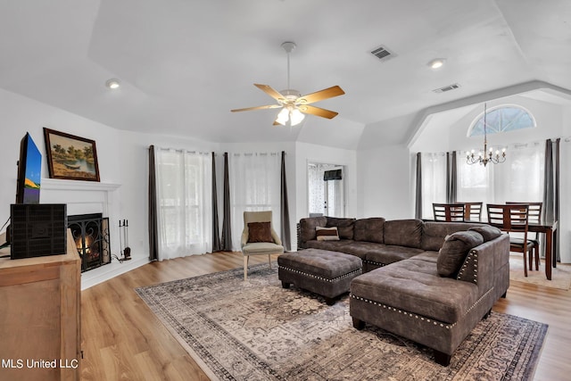 living room with lofted ceiling, ceiling fan with notable chandelier, and light hardwood / wood-style floors