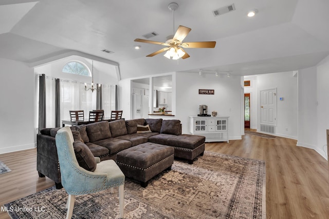 living room with light hardwood / wood-style flooring, lofted ceiling, and ceiling fan with notable chandelier