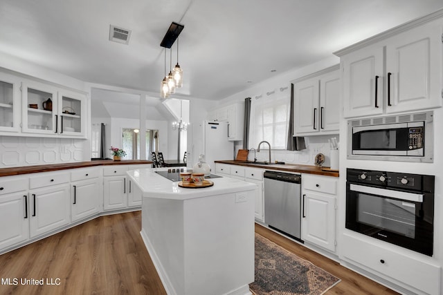 kitchen with white cabinetry, a healthy amount of sunlight, black appliances, and an inviting chandelier