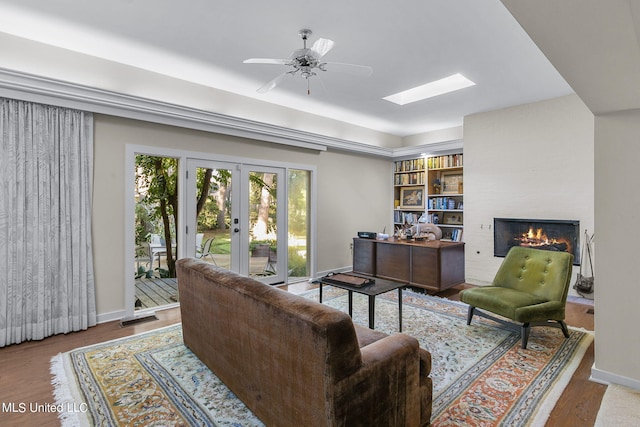 living room with french doors, wood-type flooring, a fireplace, and ceiling fan