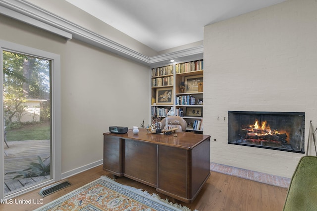 office featuring hardwood / wood-style floors and a brick fireplace