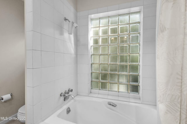 bathroom with toilet and tiled shower / bath