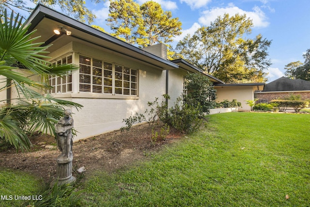 view of property exterior with a patio area and a lawn