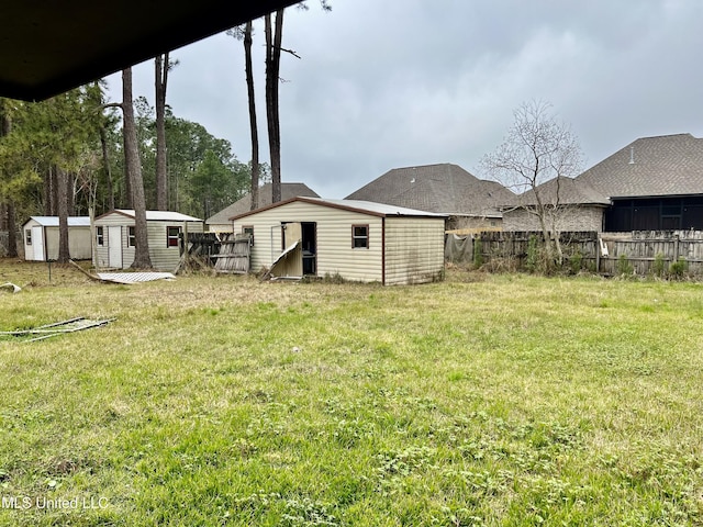 view of yard with an outbuilding, fence, and a shed