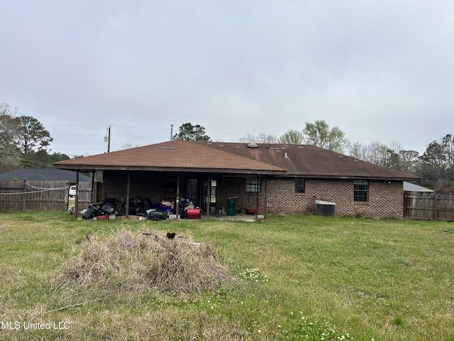 rear view of house with brick siding, a lawn, and fence