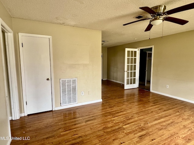 unfurnished room with ceiling fan, visible vents, a textured ceiling, and wood finished floors