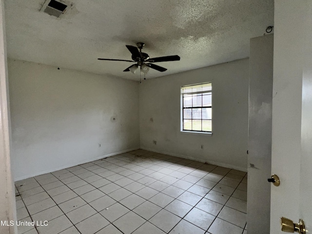 empty room with light tile patterned floors, baseboards, visible vents, ceiling fan, and a textured ceiling