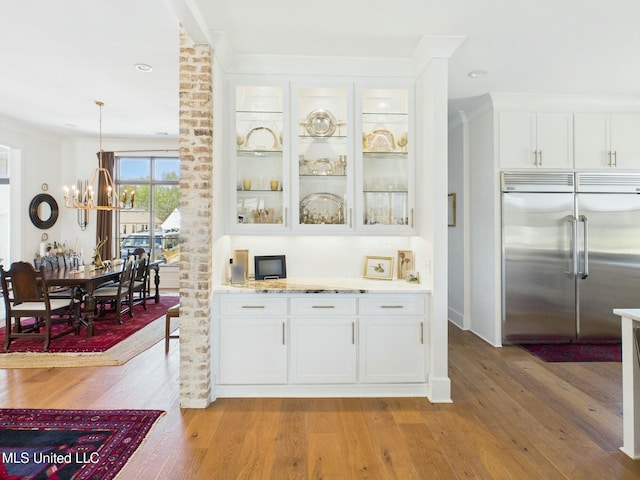 103 Honours Ln, Madison, MS 39110 - bar featuring ornamental molding, a chandelier, light wood-style flooring, stainless steel built in refrigerator, and hanging light fixtures