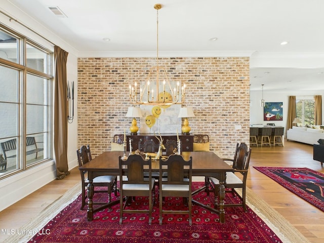 103 Honours Ln, Madison, MS 39110 - dining area with a notable chandelier, brick wall, crown molding, visible vents, and wood finished floors