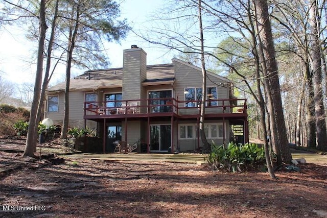 back of property with a chimney and a deck