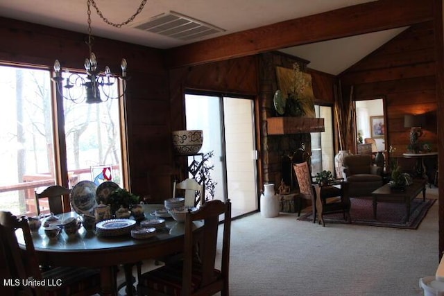 dining room with visible vents, vaulted ceiling with beams, carpet, a chandelier, and a stone fireplace