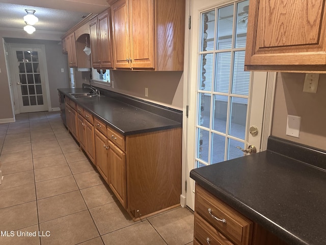 903 Westwood St, Pascagoula, MS 39567 - kitchen with dark countertops, a sink, brown cabinetry, baseboards, and light tile patterned floors