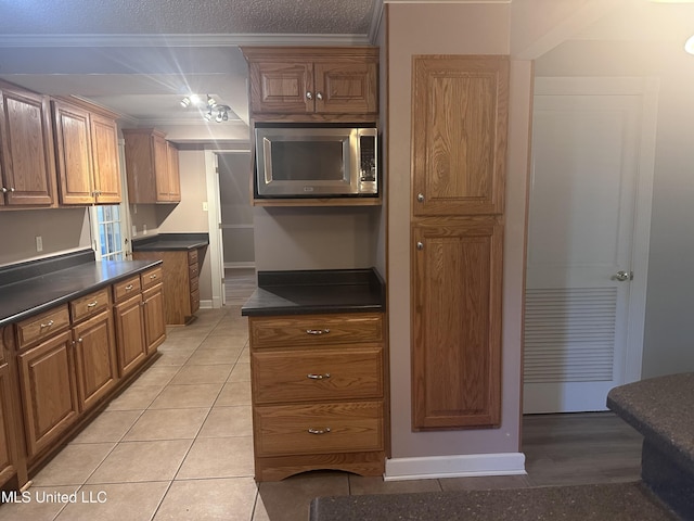 903 Westwood St, Pascagoula, MS 39567 - kitchen with brown cabinetry, dark countertops, baseboards, stainless steel microwave, and ornamental molding