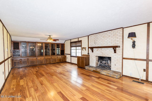 unfurnished living room featuring light hardwood / wood-style floors, a fireplace, and ceiling fan