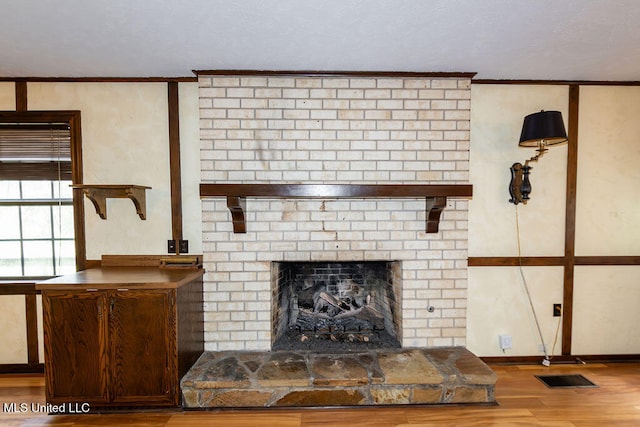 unfurnished living room with crown molding, hardwood / wood-style flooring, and a brick fireplace