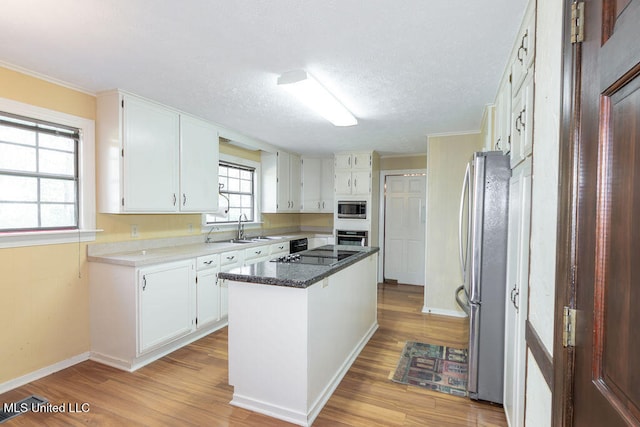 kitchen with white cabinets, a kitchen island, appliances with stainless steel finishes, light hardwood / wood-style flooring, and plenty of natural light