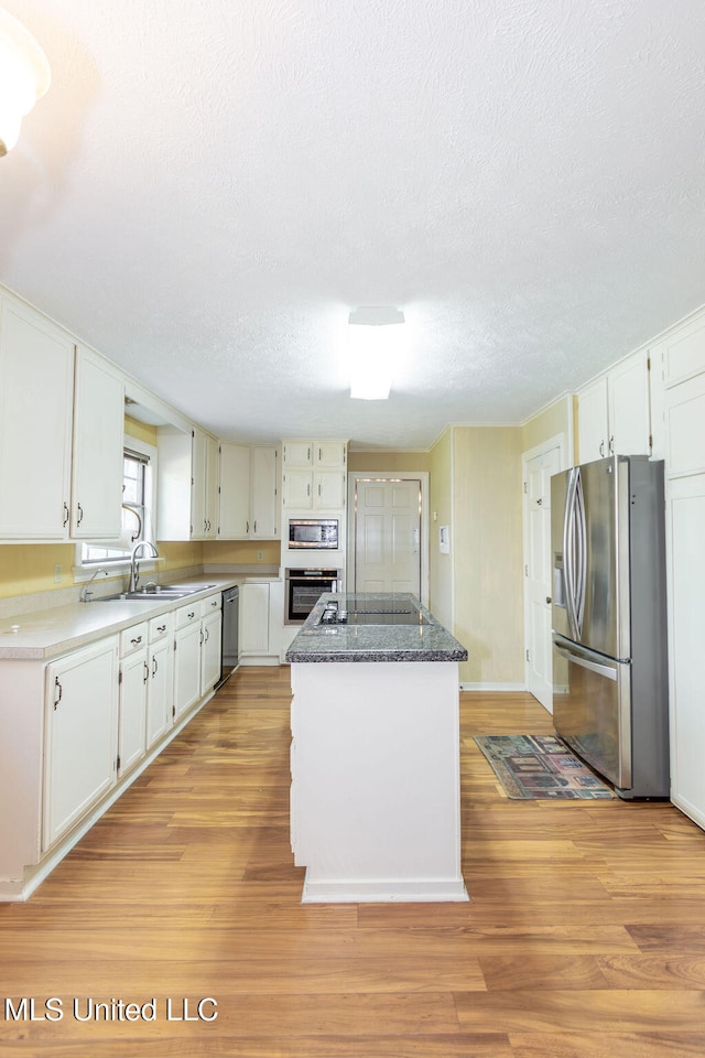 kitchen with white cabinetry, appliances with stainless steel finishes, light hardwood / wood-style flooring, and a kitchen island