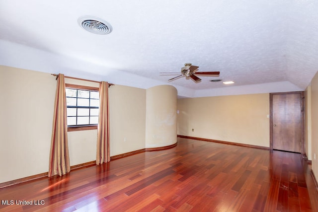 empty room featuring lofted ceiling, hardwood / wood-style floors, a textured ceiling, and ceiling fan