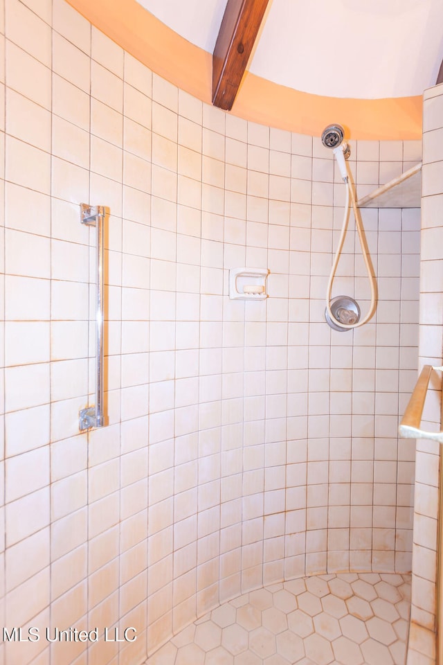 bathroom with beam ceiling and tiled shower